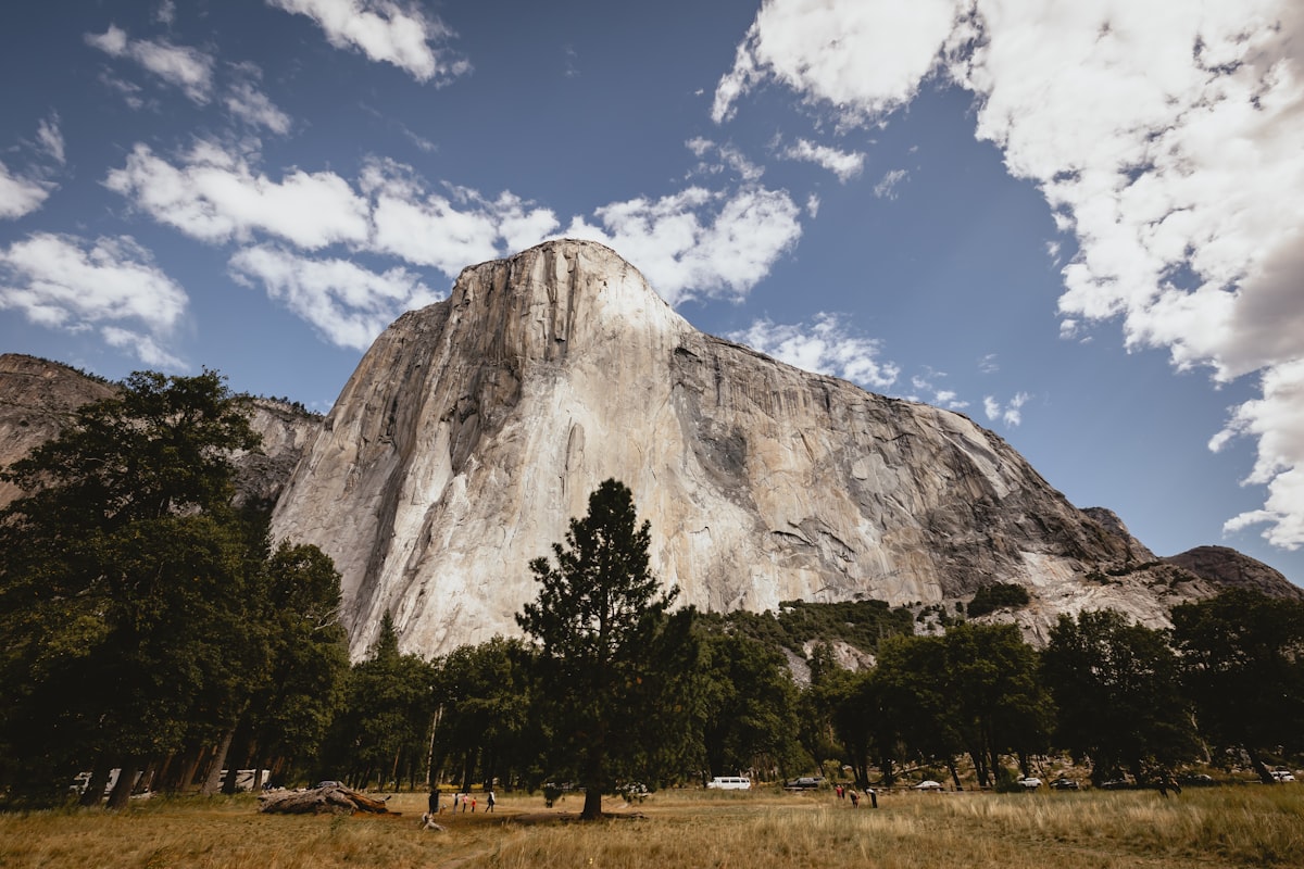El Capitan's massive granite cliff face rising above the Yosemite Valley floor under a partly cloudy sky
