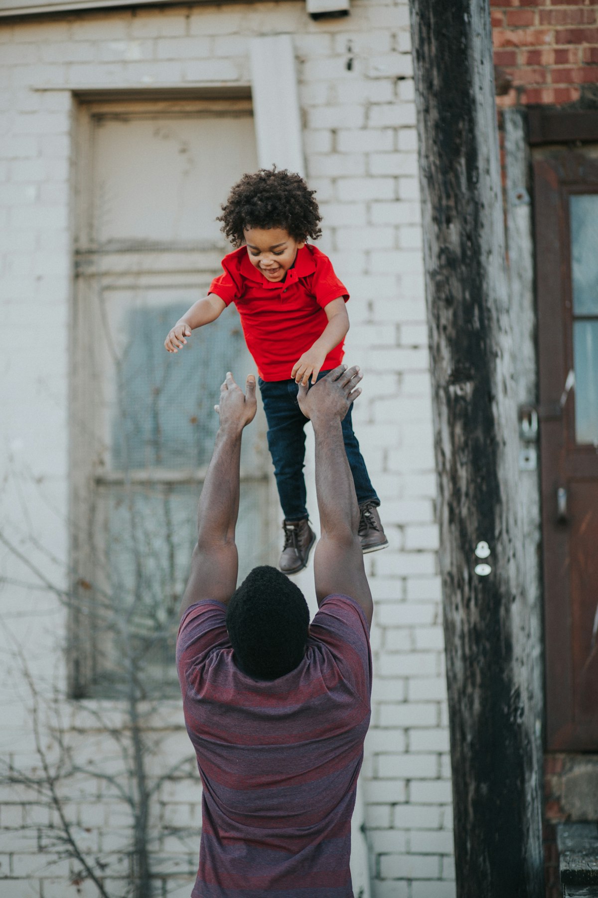 A father tossing his laughing son into the air outdoors