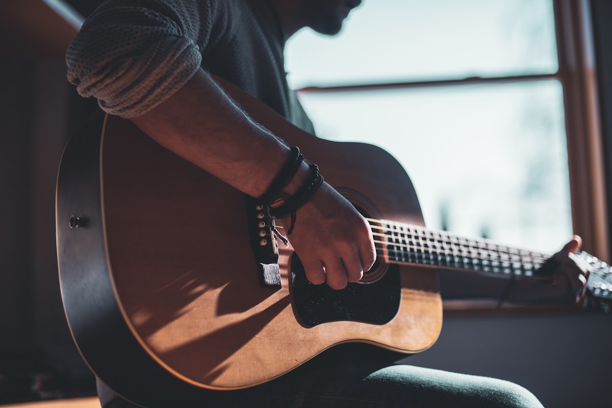 Close-up of a hand fretting an acoustic guitar while playing