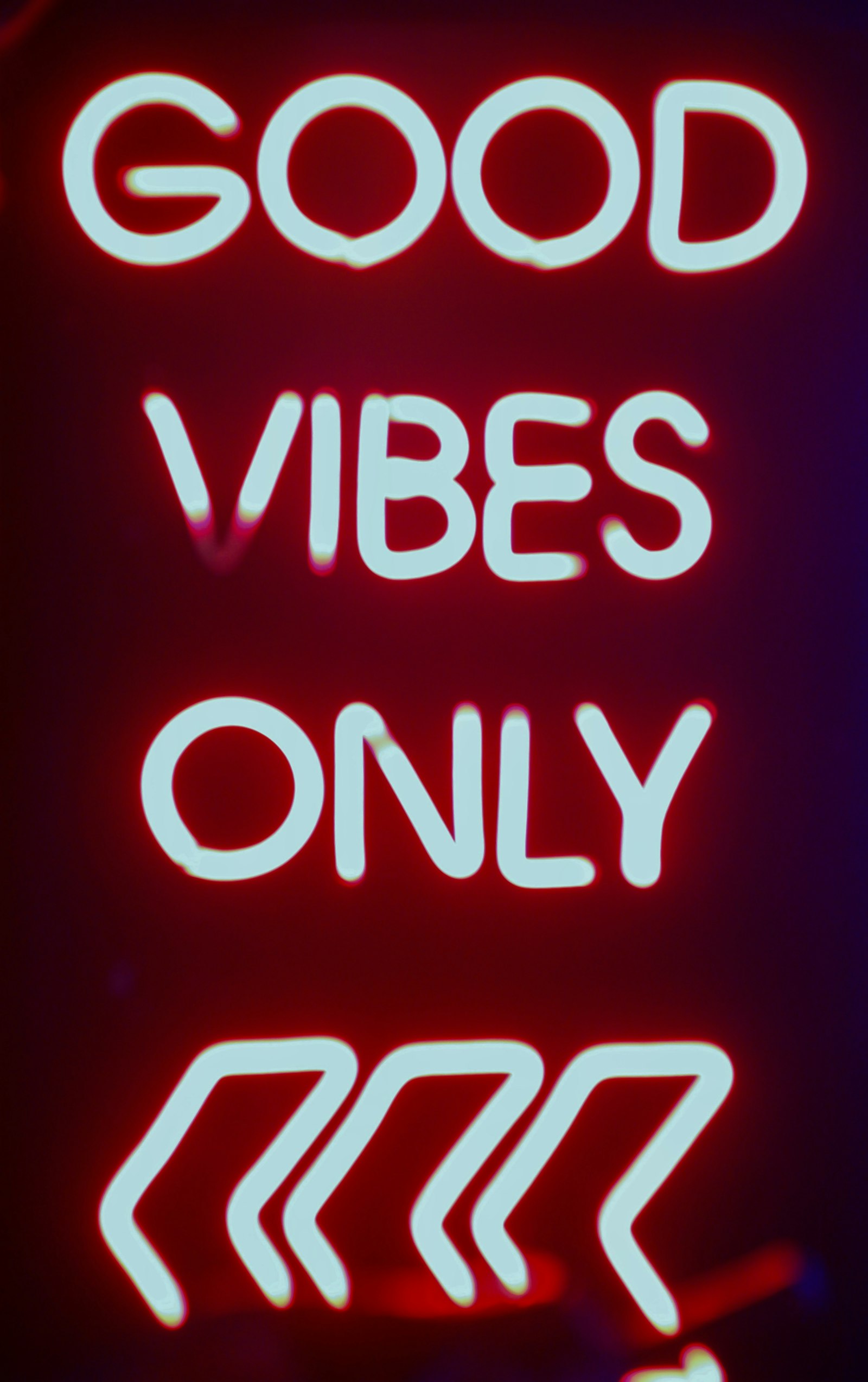 A red neon sign reading GOOD VIBES ONLY glowing in a dark room