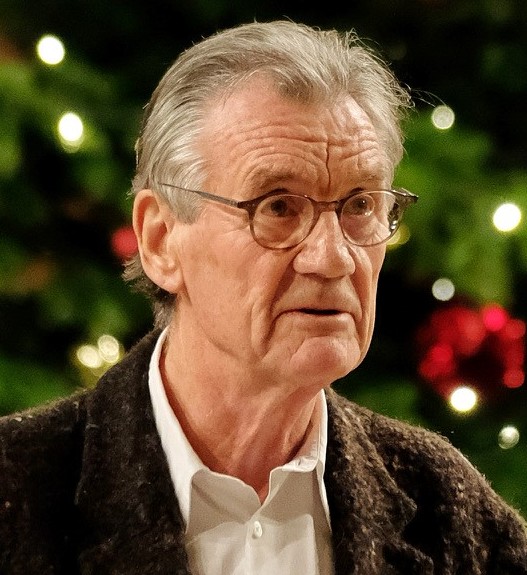 Michael Palin, close-up portrait, gray hair and round glasses.